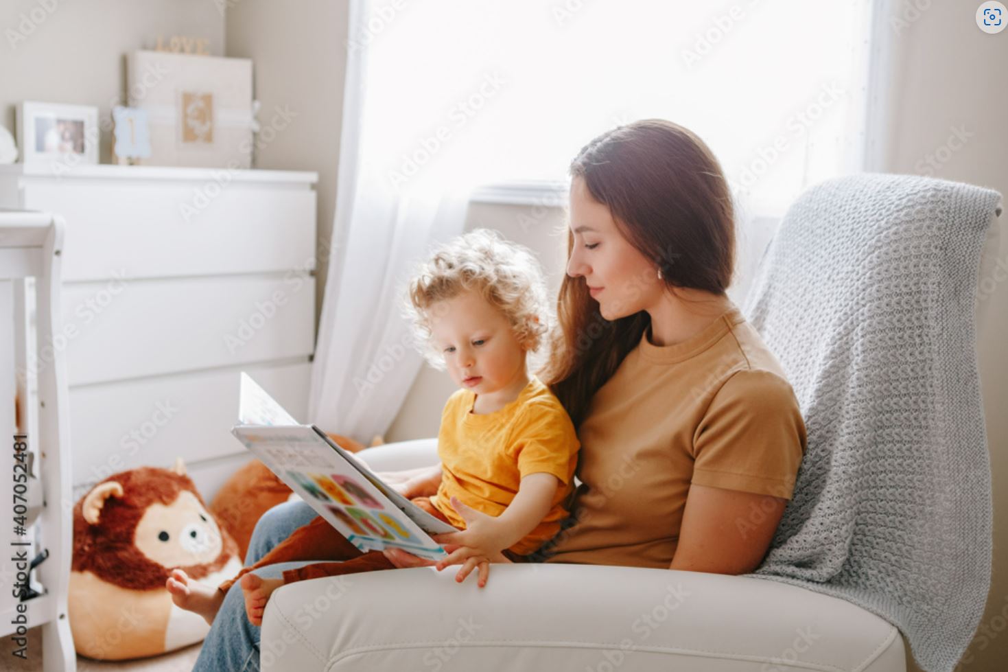 A woman and child sitting on the couch reading.